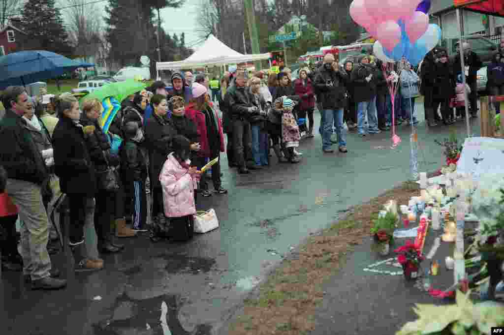 Seorang bocah menunjuk ke arah lilin-lilin yang dinyalakan saat menggelar doa untuk para korban penembakan di Newtown, Connecticut, 16 Desember 2012. (AFP Photo/ Emmanuel DUNAND)