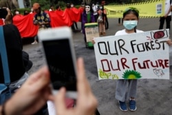 Seorang gadis mengenakan masker berpose saat Asia Climate Rally, di luar Monumen Nasional (Monas) di Jakarta, 27 November 2020. (Foto: REUTERS/Willy Kurniawan)