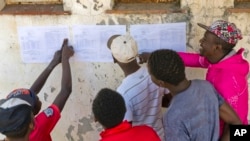 Les Zimbabwéens vérifient les résultats affichés à l'extérieur d'un bureau de vote à Bulawayo, au Zimbabwe, le 31 juillet 2018. 