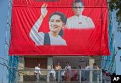 Leader of Myanmar's National League for Democracy party, Aung San Suu Kyi, center, delivers a speech from a balcony of the party headquarters in Yangon, Myanmar, Monday, Nov. 9, 2015.