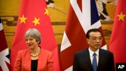 British Prime Minister Theresa May, left, and Chinese Premier Li Keqiang attend a signing ceremony at the Great Hall of the People in Beijing, Wednesday, Jan. 31, 2018.