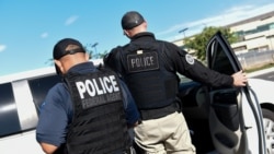 zyrtarët e ICE duke transferuar emigrantë