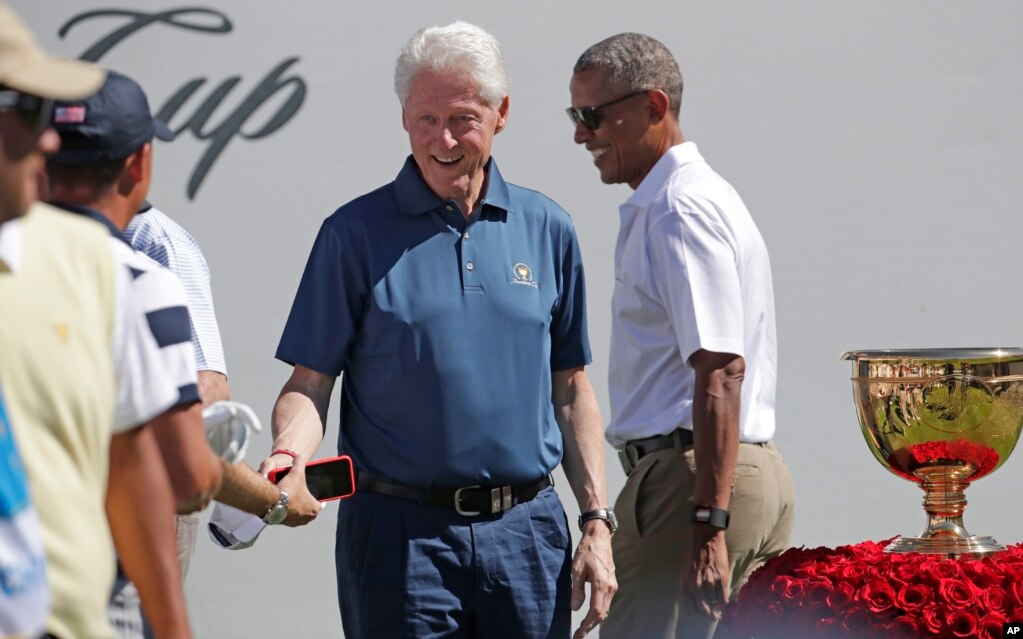 Barack Obama, à droite, et Bill Clinton saluent les membres de l&#39;équipe américaine avant le premier tour de la Coupe des Présidents au Liberty National Golf Club à Jersey City, N.J., 28 septembre 2017.