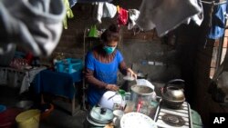 FILE - Jessica Vega, 40, who has drug-resistant tuberculosis, cooks in her home in the poor neighborhood of Carabayllo in Lima, Peru, Sept. 30, 2015. The world is making progress lifting people out of such extreme poverty.