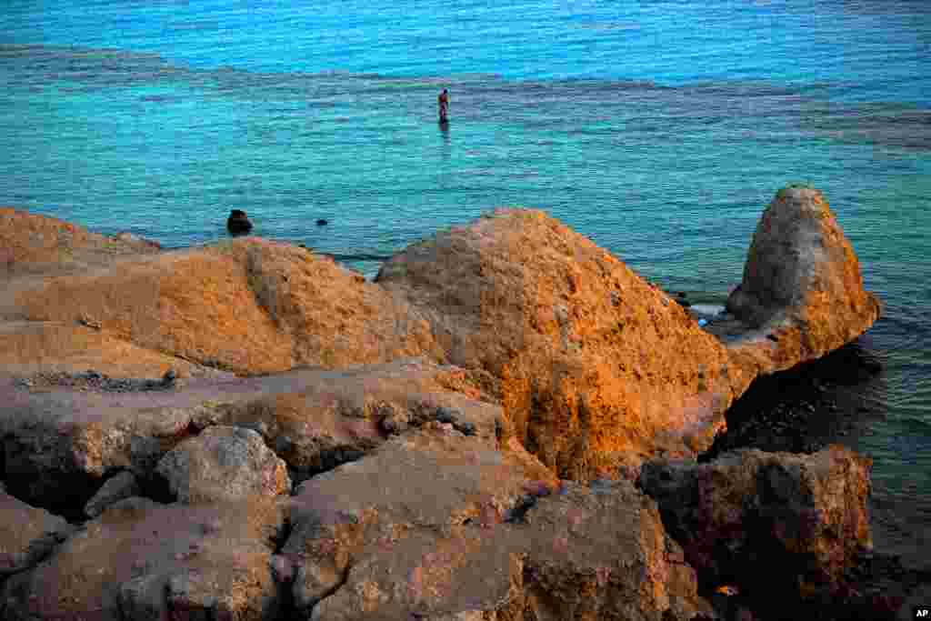 In this picture taken, June 25, 2015, a tourist enjoys the sun setting over the Red Sea in Sharm El-Sheikh, Egypt.