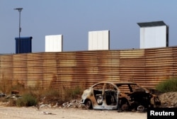 FILE - Prototypes for U.S. President Donald Trump's border wall with Mexico are seen behind the current border fence in this picture taken from the Mexican side of the border in Tijuana, Oct. 12, 2017.