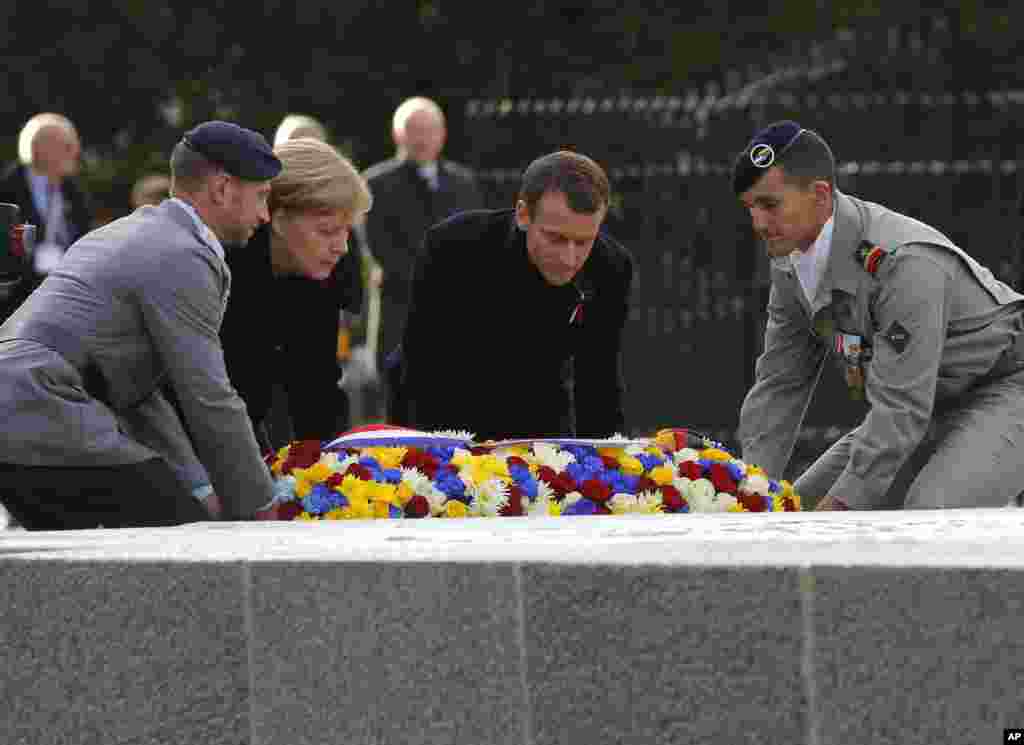 French President Emmanuel Macron, second right, and German Chancellor Angela Merkel lay a wreath during a ceremony in Compiegne, north of Paris, where the vanquished Germans and victorious but exhausted Allies put an end to World War 1, Nov. 10, 2018.