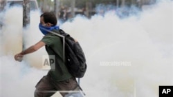 A man runs through smoke of tear gas fired up by riot police in Istanbul, Turkey, Friday, May 31, 2013. Riot police used tear gas and pressurized water to quash a peaceful demonstration by hundreds of people staging a sit-in to try to prevent the demoliti