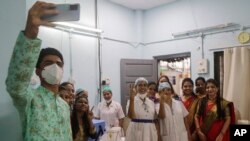 Health workers celebrate India administering 1 billion doses of COVID-19 vaccine, at Rajawadi hospital in Mumbai, India, Oct. 21, 2021.
