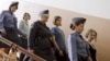 Feminist Russian punk group Pussy Riot members, Nadezhda Tolokonnikova, center, Maria Alekhina, front, and Yekaterina Samutsevich, are escorted to a glass cage at a court room in Moscow, Russia, August 17, 2012. 
