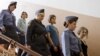 Feminist Russian punk group Pussy Riot members, Nadezhda Tolokonnikova, center, Maria Alekhina, front, and Yekaterina Samutsevich, are escorted to a glass cage at a court room in Moscow, Russia, August 17, 2012. 