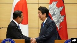 Japanese Prime Minister Shinzo Abe, right, and Cambodia's Prime Minister Hun Sen shake hands after their meeting at Abe's office in Tokyo Monday, Oct. 8, 2018. (AP Photo/Eugene Hoshiko, Pool)