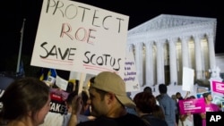 A demonstrator holds a sign as protesters gather in front of the Supreme Court in Washington, July 9, 2018, after President Donald Trump announced Judge Brett Kavanaugh as his Supreme Court nominee.