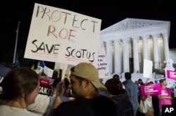 FILE - A demonstrator holds a sign as protesters gather in front of the Supreme Court in Washington, July 9, 2018, after President Donald Trump announced Judge Brett Kavanaugh as his Supreme Court nominee.