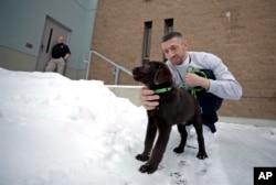 Inmate Justin Martin takes a chocolate lab puppy outside at Merrimack County Jail in Boscawen, N.H., Jan. 8, 2019.