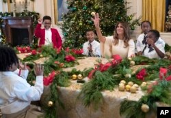La primera dama de EE.UU., Melania Trump juega con un niño invitado a ver los adornos de la Casa Blanca lanzándole uno de los globos de la decoración.