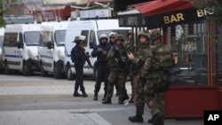 프랑스 경찰이 18일 파리 북부 외곽 생드니에서 테러 용의자들의 은신처를 급습한 가운데, 현장 주변에 경찰 특부수대원과 군인들이 서있다.