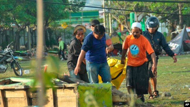 Varias personas cargan el cuerpo de una víctima del tsunami en Palu, Sulawesi central, Indonesia, el domingo 30 de septiembre del 2018.