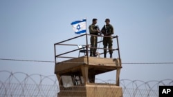 Dua tentara Israel siaga dengan senjata mereka di atas menara pengawas, dekat perbatasan Israel-Gaza.