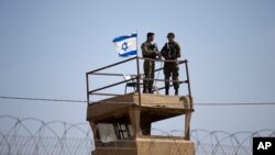 FILE - Israeli soldiers stand guard atop a watch tower along the Israel-Gaza Strip border, May 15, 2018.