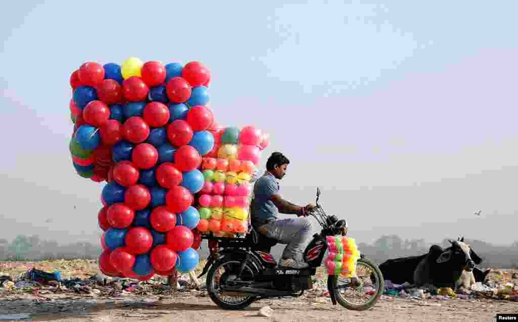 Seorang membawa bola-bola plastik dengan motornya di New Delhi, India.