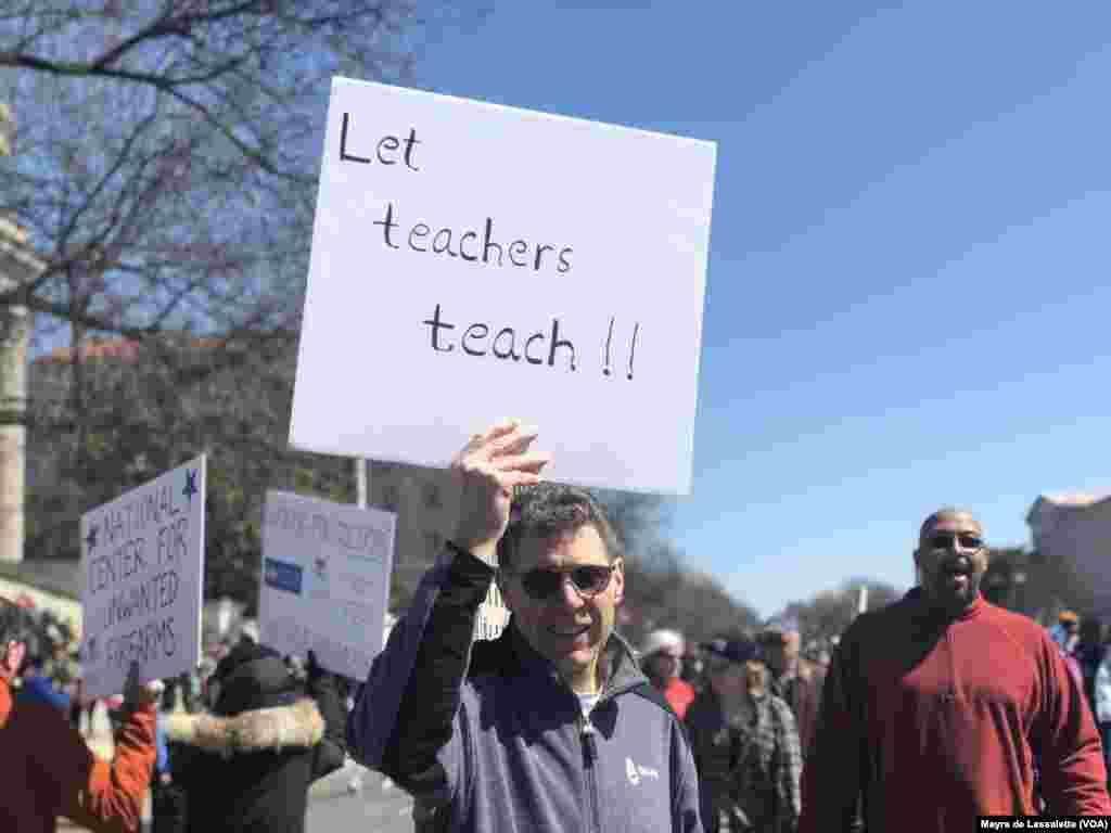 Um manifestante ergue um cartaz dizendo: "Deixem os professores ensinar"