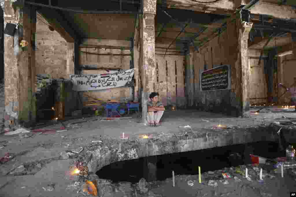 A man sits by a makeshift memorial inside a burned mall by a massive truck bombing last Sunday in the Karada neighborhood of Baghdad, Iraq. Attack claimed by Islamic State group killed at least 186 people.