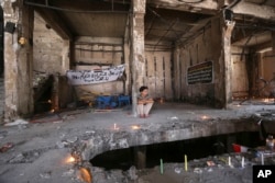 FILE - A man sits amid a makeshift memorial inside a burned mall at the scene of a massive truck bombing last Sunday that killed at least 186 people and was claimed by the Islamic State group, in the Karada neighborhood of Baghdad, Iraq, July 10, 2016.