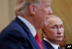 Russian President Vladimir Putin, right, looks over towards U.S. President Donald Trump, left, as Trump speaks during their joint news conference at the Presidential Palace in Helsinki, Finland, July 16, 2018.