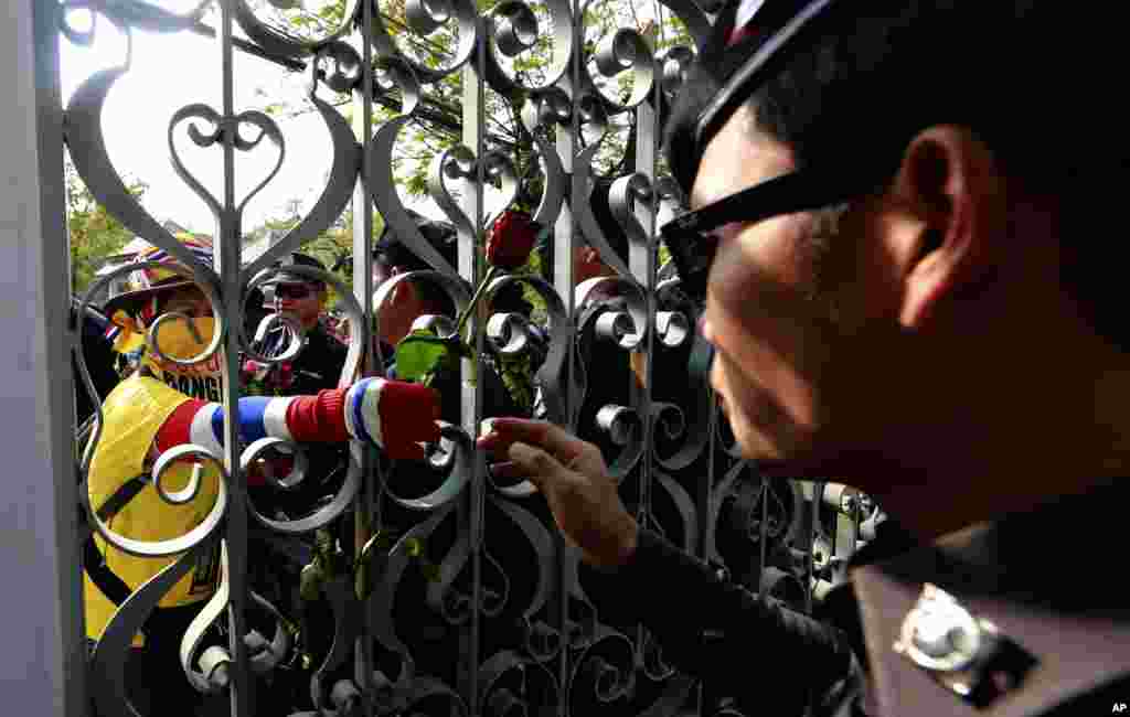 A Thai policeman, right, is handed a flower from an anti-government protester during a police force rotation at the government house in Bangkok, Thailand.