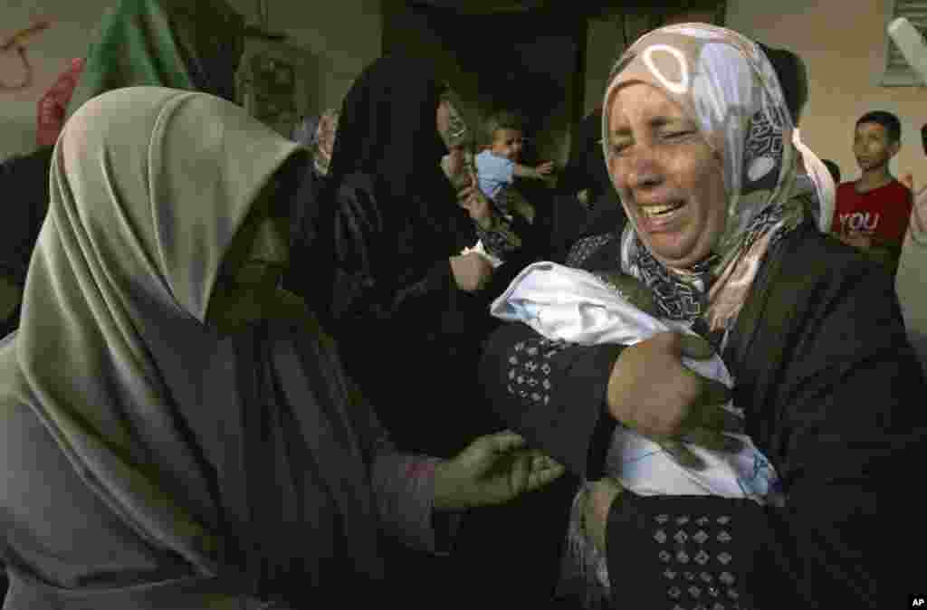 A relative holds a dead baby during the funeral of members of Al Ghoul family in the Rafah refugee camp, in the southern Gaza Strip. At least 40 people were inside the Al Ghoul family building in Rafah when it was targeted by Israeli jet fighters, according to the Red Crescent and Gaza health official Ashraf al-Kidra.