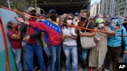 En esta imagen de archivo, tomada el 16 de septiembre de 2021, residentes esperan detrás de una cinta que sirve de barrera ante un centro de vacunación, donde buscan recibir la segunda dosis de la rusa Sputnik V contra el COVID-19, en Caracas, Venezuela.