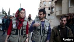 Members of OCHA (Office for the Coordination of Humanitarian Affairs), part of the United Nations, walk in the rebel held besieged town of Kafr Batna, on the outskirts of Damascus, during a distribution of humanitarian aid, Feb. 23, 2016. 