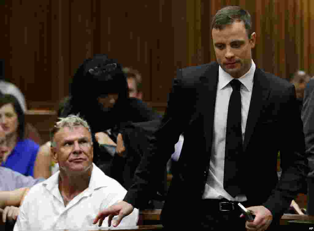 Oscar Pistorius crosses paths with former soccer player Mark Batchelor during the proceedings, Pretoria, Oct. 16, 2014.