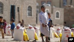 A displaced boy who fled Saada province, northwest of Sana'a with his family, waits for relief supplies during a food distribution by Yemeni volunteers in Sana'a, Yemen, Dec. 17, 2015.