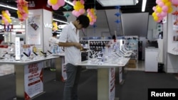 FILE - A customer look at a mobile phone on display at an electronics market in Shanghai, China.