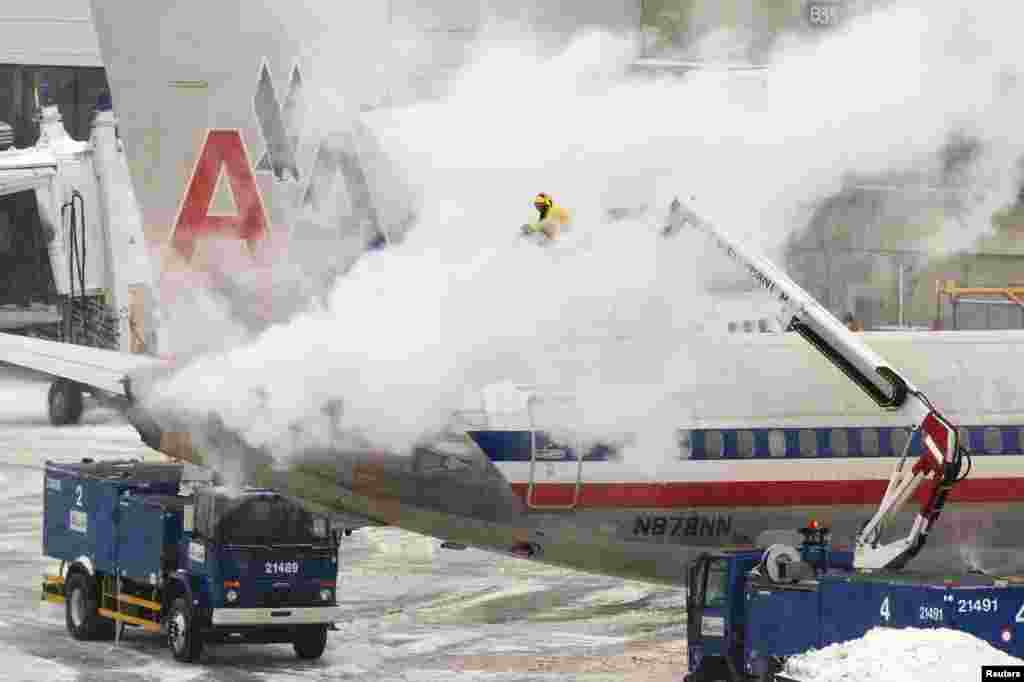 A equipa da American Airlines lança im spray descongelante para cima de um avião em Boston, Jan. 2, 2014. 
