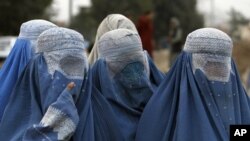 Afghan women wait for food distributed by Afghanistan's Interior Ministry to the internally displaced families from Helmand province, during the holy month of Ramadan at a refugee camp in Kabul (File Photo - August 28, 2011).