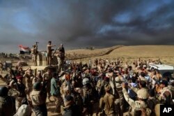 Army soldiers raise their weapons in celebration on the outskirts of Mosul, Iraq, Oct. 20, 2016.