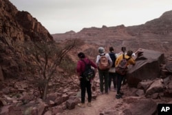 In this March 29, 2019 photo, tourists stop to look at the scenery on a trek in the mountains near Wadi Sahw led by Beduin women, Abu Zenima, in South Sinai, Egypt. (AP Photo/Nariman El-Mofty)