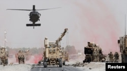 Pasukan AS memeriksa kerusakan pada kendaraan baja milik koalisi militer pimpinan NATO setelah serangan bom bunuh diri di provinsi Kandahar, 2 Agustus 2017.