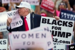 Republican presidential candidate Donald Trump kisses a "Women for Trump" sign during a campaign rally in Lakeland, Florida, Oct. 12, 2016.