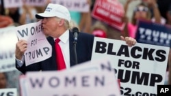 Republican presidential candidate Donald Trump kisses a "Women for Trump" sign during a campaign rally in Lakeland, Florida, Oct. 12, 2016. Trump's poll numbers sank following allegations by numerous women that he had made unwanted sexual advances toward them.