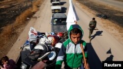 A displaced Iraqi child holds a white flag as he and his family flee during a battle with Islamic State militants in Kokjali village near Mosul, Iraq, Nov. 3, 2016. 