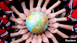 Students pose for a photo with a globe during a campaign to mark World Earth Day.