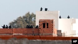 Tunisian anti-terrorist police forces (BAT) stand on roofs near a house where suspected Islamist militants were hidden in Raoued, near Tunis, Tuesday, Feb.4, 2014.