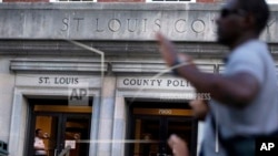 St. Louis county police officer stands inside headquarters as protesters march while grand jury begins hearing evidence to weigh possible charges against Ferguson patrolman who fatally shot 18-year-old Michael Brown, Clayton, Mo., Aug. 20, 2014.
