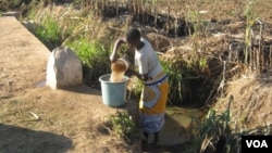 In Malawi, woman in the central district of Dedza gathers water (VOA/L. Masina) 