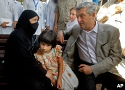 FILE - U.N. High Commissioner for Refugees Filippo Grandi talks to an Afghan refugee woman during his visit to the UNHCR's Repatriation Center in Peshawar, Pakistan, June 23, 2016.