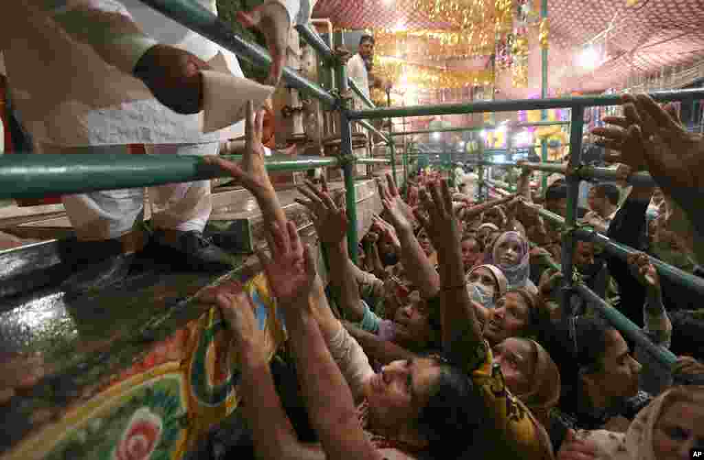 Women jostle to get free milk at a distribution point during the celebrations of the three-day annual festival of famous saint Al-Sheikh Ali Bin Usman Al-Hajveri known as Data Ganjbaksh at his shrine, in Lahore, Pakistan, Sept. 26, 2021.